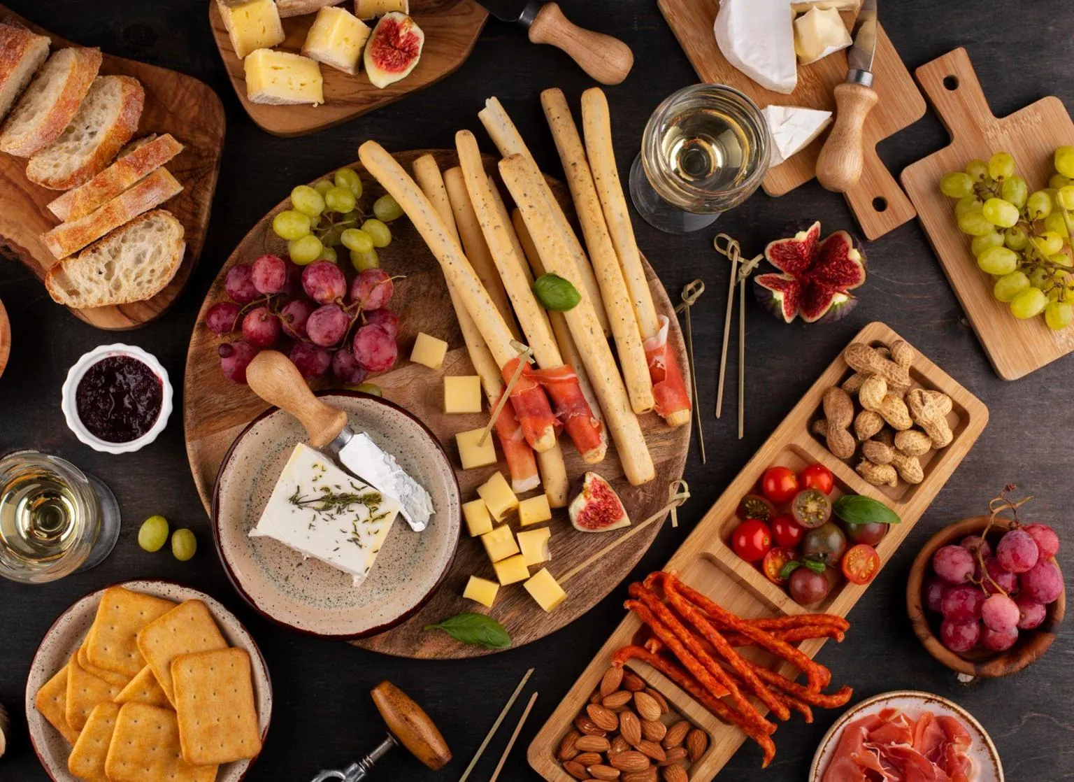 A board of cheeses, bread, grapes and breadsticks